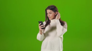 Woman adjusting dark hair while taking selfie on mobile