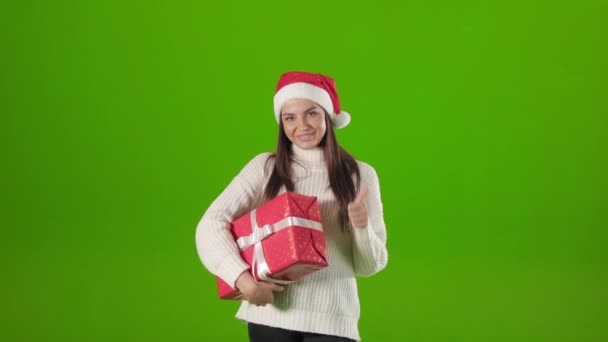 Frau mit Weihnachtsmannhut hält Geschenkbox in der Hand und zeigt Daumen hoch — Stockvideo