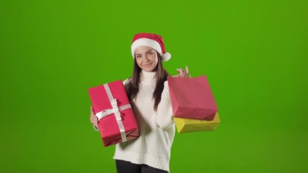 Mujer en sombrero de santa celebración de regalo de Navidad y bolsas de compras — Vídeos de Stock