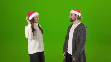 Noel Baba şapkalı neşeli çift stüdyoda beşlik çakıyor.