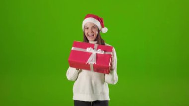 Noel Baba şapkalı kadın stüdyoda hediye kutusuyla dans ediyor.