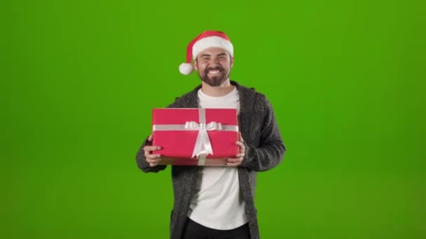 Homme en santa chapeau dansant avec présent sur fond vert. — Video