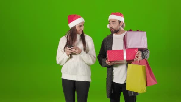 Woman using mobile while man holding many presents and bags — Stock Video