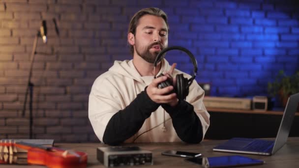 Músico eximing nuevos auriculares en el estudio oscuro — Vídeo de stock