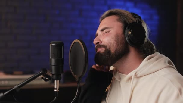 Hombre con auriculares cantando en micrófono en estudio de grabación — Vídeos de Stock