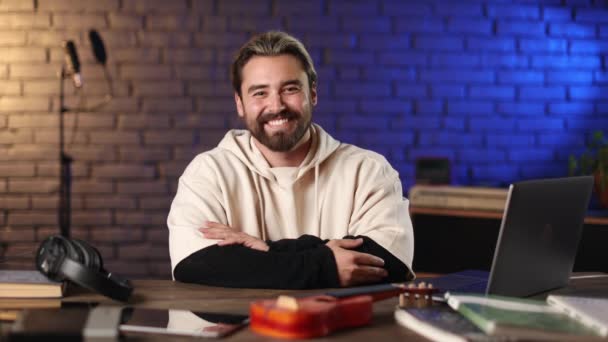 Bărbat cu barbă fericită care stă la birou cu laptop și ukulele — Videoclip de stoc
