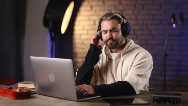 Muž těší novou píseň ve sluchátkách během práce ve studiu — Stock video