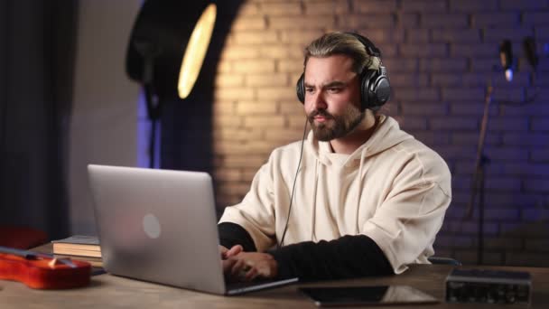 Homme dans les écouteurs travaillant sur ordinateur portable et tablette au studio — Video