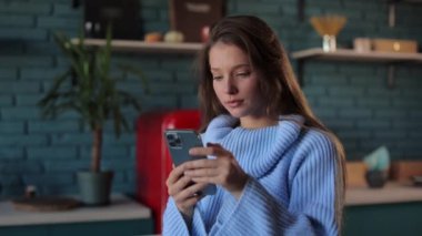 Evde akıllı telefon kullanan genç bir kadının portresi