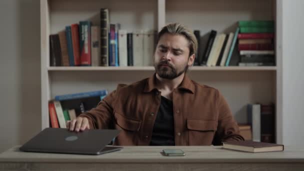 Человек медитирует, сидя за столом с ноутбуком — стоковое видео
