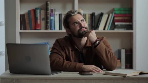 Pensive man using laptop, smartphone and book at desk — Stock Video