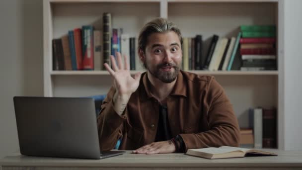 Homem acenando a mão, falando na câmera e usando laptop — Vídeo de Stock