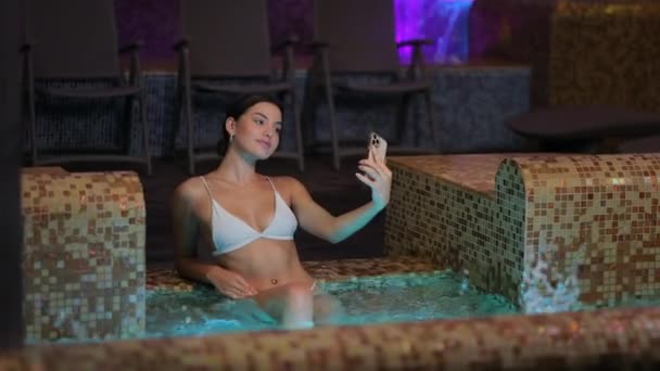 Mujer joven tomando selfie en smartphone en jacuzzi — Vídeos de Stock