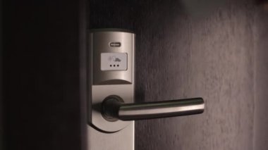 Modern otelin kapısını açmak için elektronik anahtar kullanan bir kadın. Kadının özel odasına güvenlik koduyla girerken yakın plan.