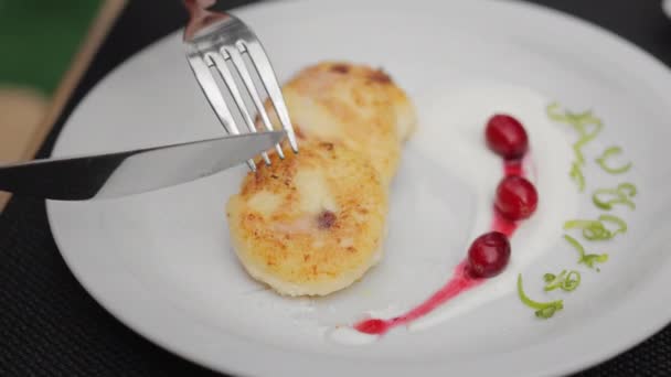在早餐吃新鲜美味的糖浆时 用刀叉把女人关起来 美味的奶酪煎饼 盘上有樱桃酸奶油 — 图库视频影像
