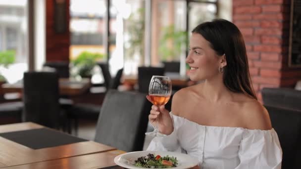 장미 술을 마시고 식당에서 샐러드를 먹는 여자 — 비디오