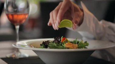 Kadın eli restoranda lezzetli salataya limon sıkıyor.