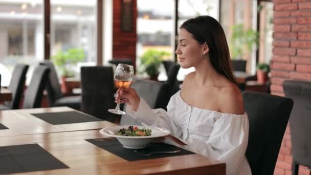 Przyjemna kobieta ciesząca się winem i sałatką w przytulnej restauracji — Wideo stockowe