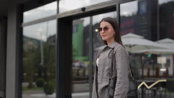 Nő stílusos viselet és napszemüveg pózol a szabadban — Stock videók