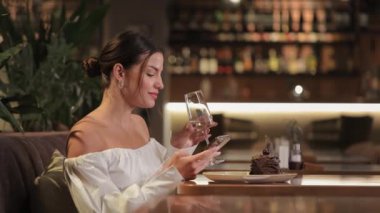 Lokantada yemek yerken cep telefonu kullanan hoş bir kadın.