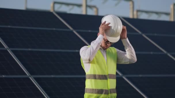 Ritratto dell'uomo che indossa il casco di sicurezza tra la stazione solare. — Video Stock