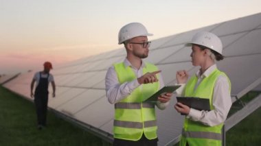 Güneş panellerini kontrol eden teknisyenler konuşurken müfettişler konuşuyor.