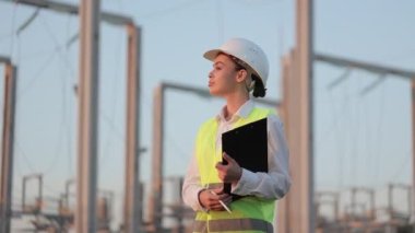 Elektrik santralinde dikilirken kameraya bakan mühendis.