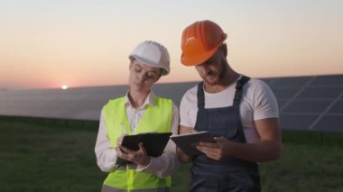 Güneş çiftliğinde tablet ve pano taşıyan iş arkadaşları.