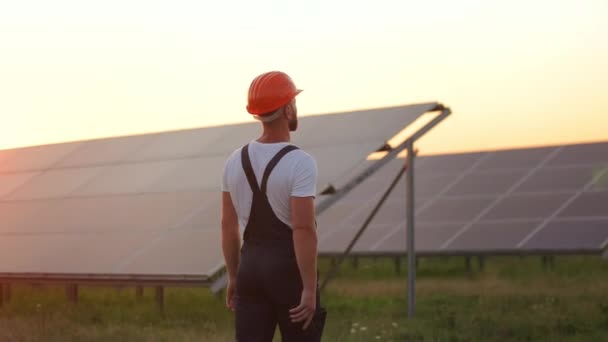 Muž v uniformě chůze na solární stanici s mobilními v rukou. — Stock video