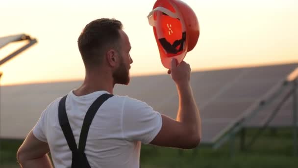 Visão traseira do homem em pé na fazenda solar e usando capacete. — Vídeo de Stock