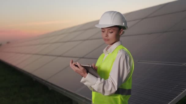 Woman standing at solar station with tablet in hands. — Stock Video