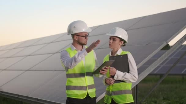 Two engineers and technician working together at solar farm. — Stock Video