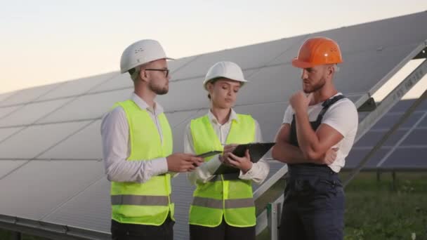 Two inspectors talking with technician at solar station. — Stock Video