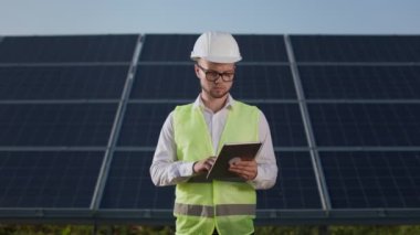 Güneş panellerini inceleyen tabletli teknisyen.