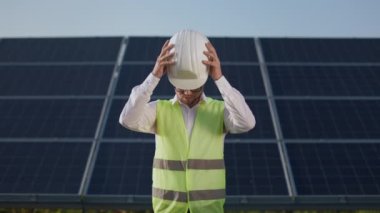 Adam güneş istasyonunda dururken beyaz kask takıyor..