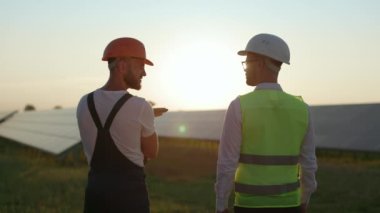 Günbatımında güneş çiftliğinde teknisyen ve mühendis konuşuyor..