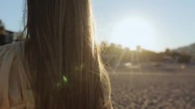 Deniz kıyısında yürüyen sarı saçlı bir kadın.