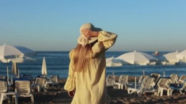 Hasır şapkalı kadın deniz kenarındaki kumlu sahilde yürümekten zevk alıyor.