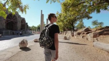 Sırt çantalı bir adam eski şehrin sokaklarında yürüyor.