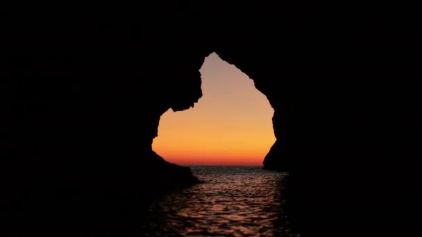 Γραφική θέα του καλοκαιρινού ηλιοβασιλέματος πάνω από τη θάλασσα μέσα από τρύπα στο σπήλαιο — Αρχείο Βίντεο