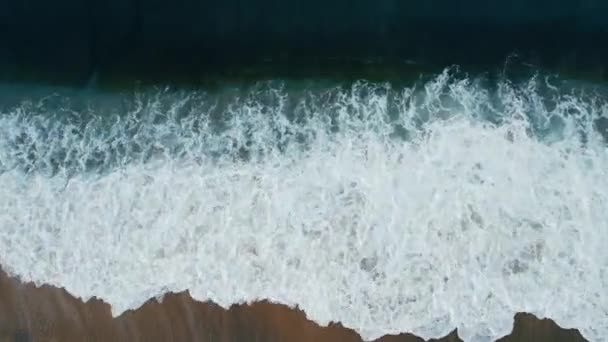 Вид с воздуха на морские волны, плескающиеся на песчаном пляже — стоковое видео