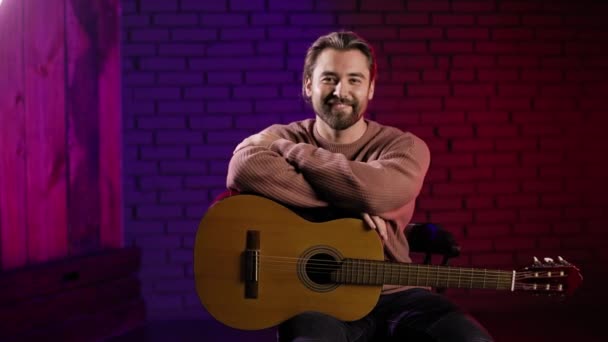 Usmívající se mužský kytarista pózující ve studiu se svým nástrojem — Stock video