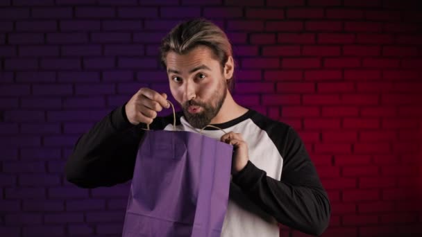 Muž stojící ve studiu a dívající se do nákupní tašky — Stock video