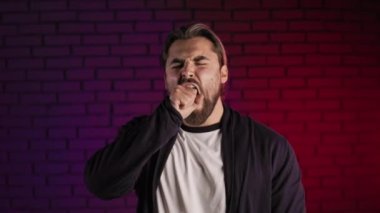 Stüdyoda esnerken ağzını yumrukla kapatan adam.