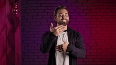 Motive olmuş adam kendinden emin konuşuyor ve elleriyle işaret ediyor.
