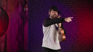 Evde şarkı söyleyen ve gitar çalan olumlu duygusal bir adam.