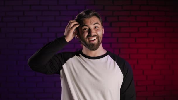 Confused man shrugging with shoulders while posing in studio — Stockvideo