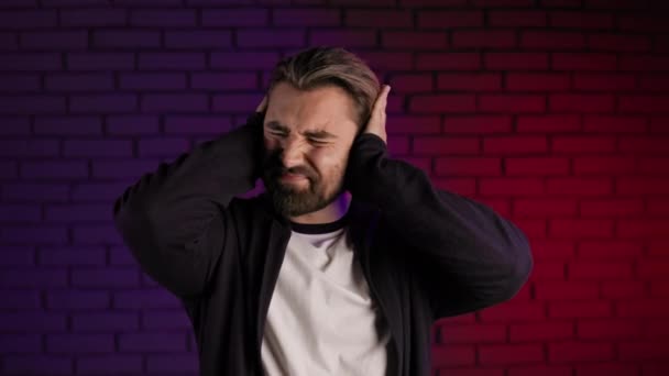 Irritated man covering ears with hands because of loud noise — Stockvideo
