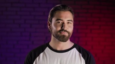 Stüdyoda poz veren pozitif sakallı genç adamın portresi.