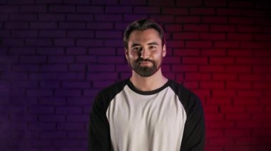 Yüzünde samimi bir gülümsemeyle stüdyoda poz veren pozitif bir adam.